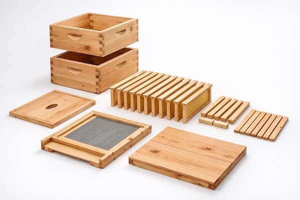 Unassembled beehive components made from raw, unstained cedar wood in an exploded view layout